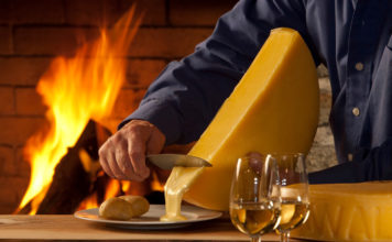 Raclette-Käse wird am Feuer erhitzt und auf den Teller geschabt.