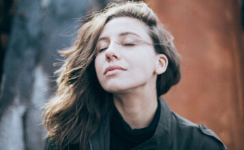 Richtiges Atmen für eine kraftvolle Gesundheit Eine junge Frau möchte im Freien richtig Atmen