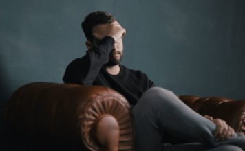 Ein gestresster Mann sitzt auf dem Sofa