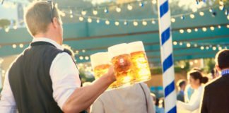 Die Bedinung am Münchner Oktoberfest bringt mehrere Maßkrüge Bier an den Tisch