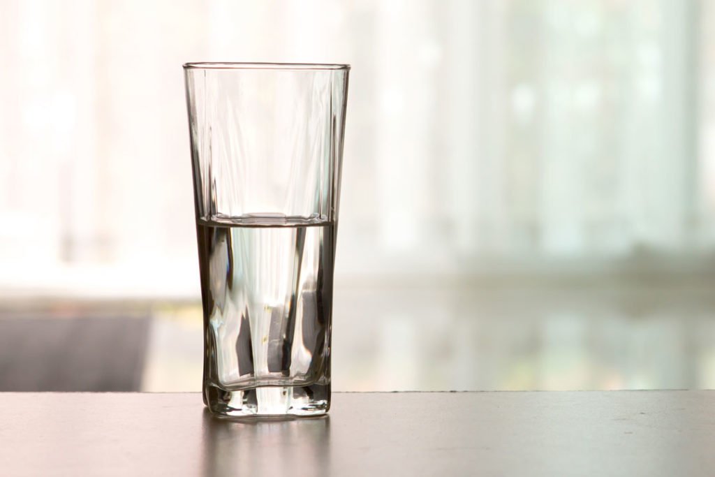 Halbleeres Wasserglas auf den Tisch