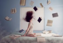 Junge Frau auf dem Bett mit vielen fliegenden Lernbücher