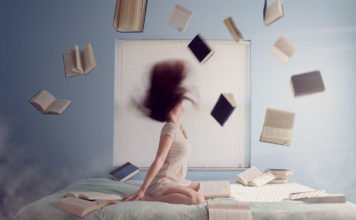 Junge Frau auf dem Bett mit vielen fliegenden Lernbücher