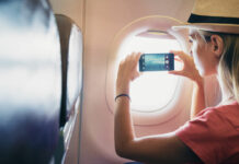 Eine junge Frau macht aus dem Flugzeugfenster ein Foto für die sozialen Netzwerke