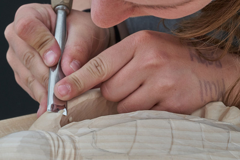 Eine Frau fertigt Schnitzereien mit Lindenholz an
