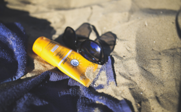 Badetuch mit Sonnenschutz und Sonnenbrille am Strand