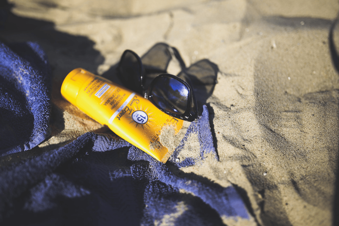 Badetuch mit Sonnenschutz und Sonnenbrille am Strand