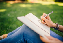 Eine Frau schreibt im Freien eine Geschichte in ihr Schreibheft