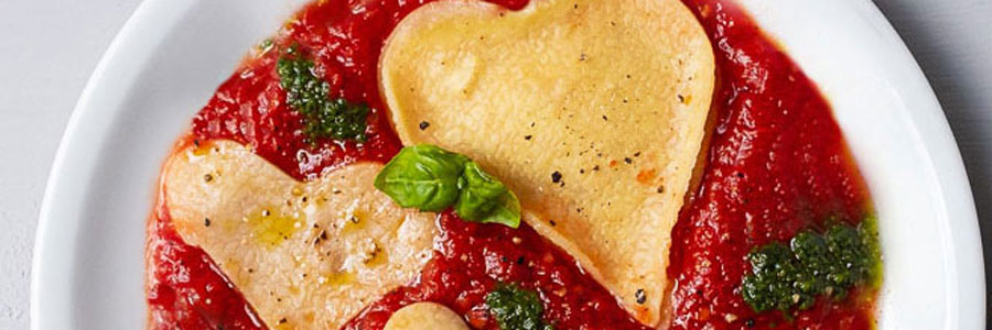 Pasta in Herzform werden zusammen mit der Tomatensoße schön angerichtet
