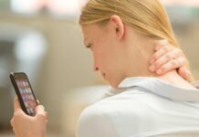 Eine junge Frau hat Nackenschmerzen aufgrund der häufigen Smartphone-Nutzung