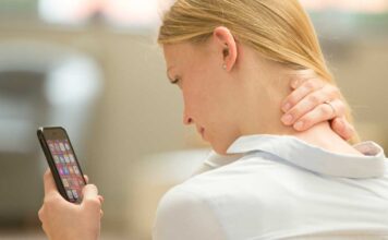 Eine junge Frau hat Nackenschmerzen aufgrund der häufigen Smartphone-Nutzung