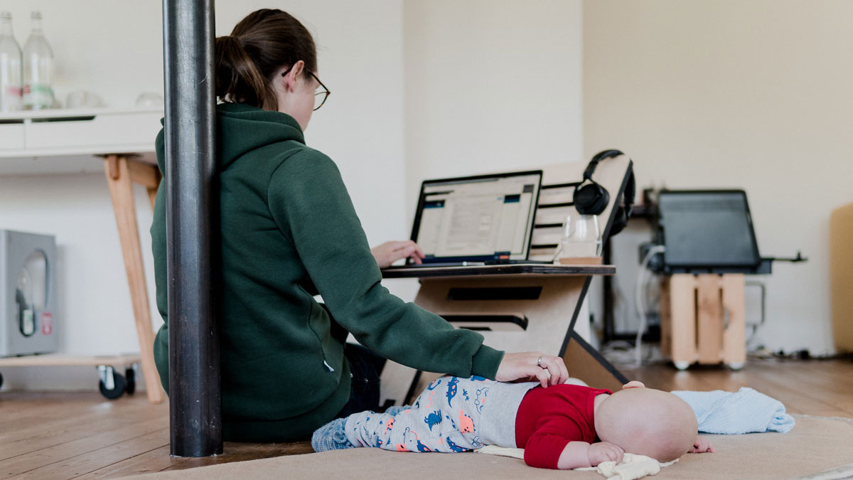 Eine selbstständige Mutter arbeitet am Computer während Baby schläft