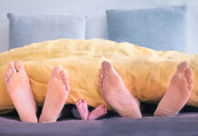 Füsse einer Frau, Kind und Mann unter der Decke als Symbol für aertgerecht schlafen