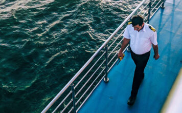 Ein Schiffsoffizier geht an der Reling entlang.